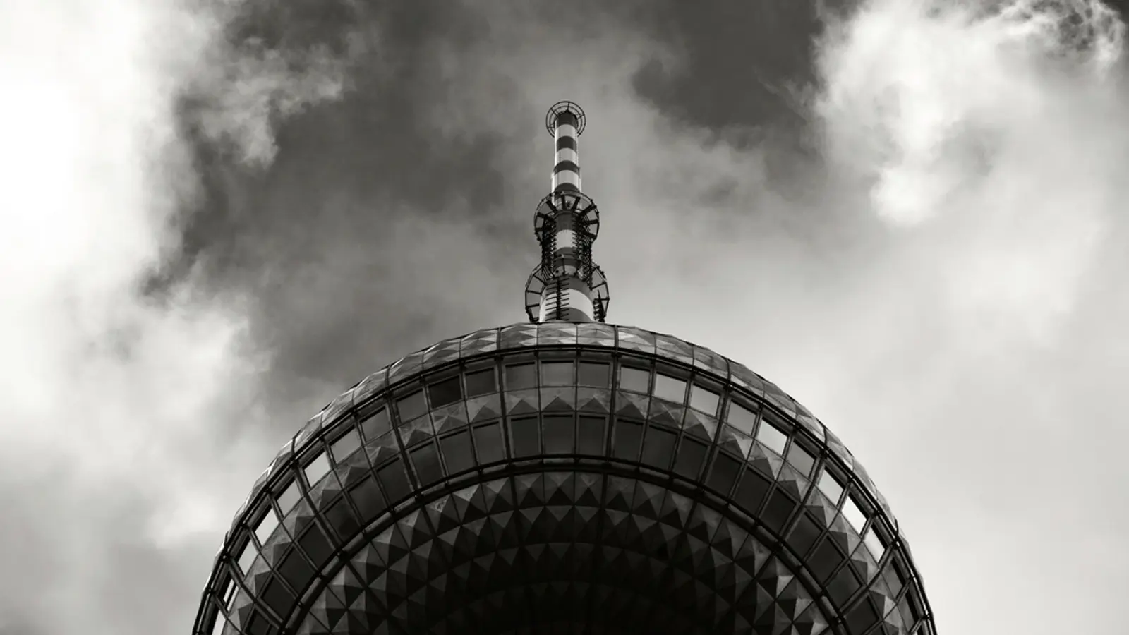 Sommet d'une tour de télévision en noir et blanc sous un ciel nuageux