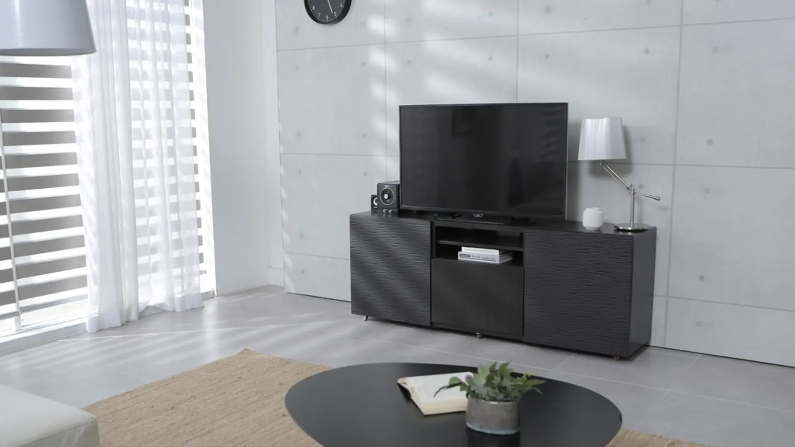 Salon minimaliste avec un téléviseur posé sur un meuble noir