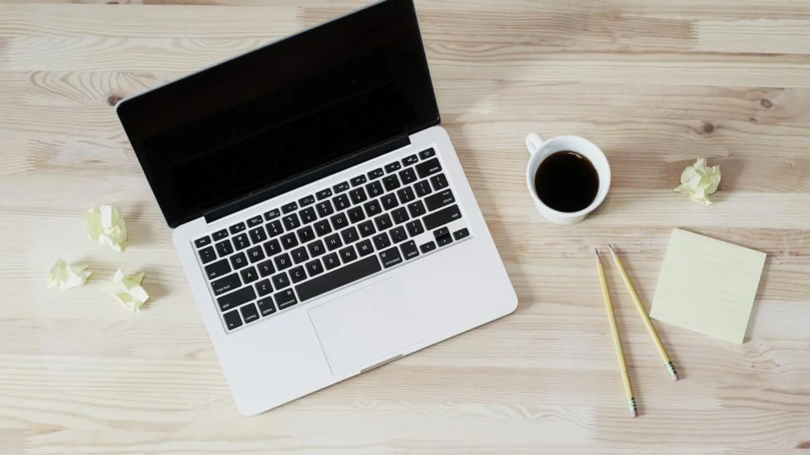 Ordinateur portable vu de dessus sur une table en bois clair avec un café
