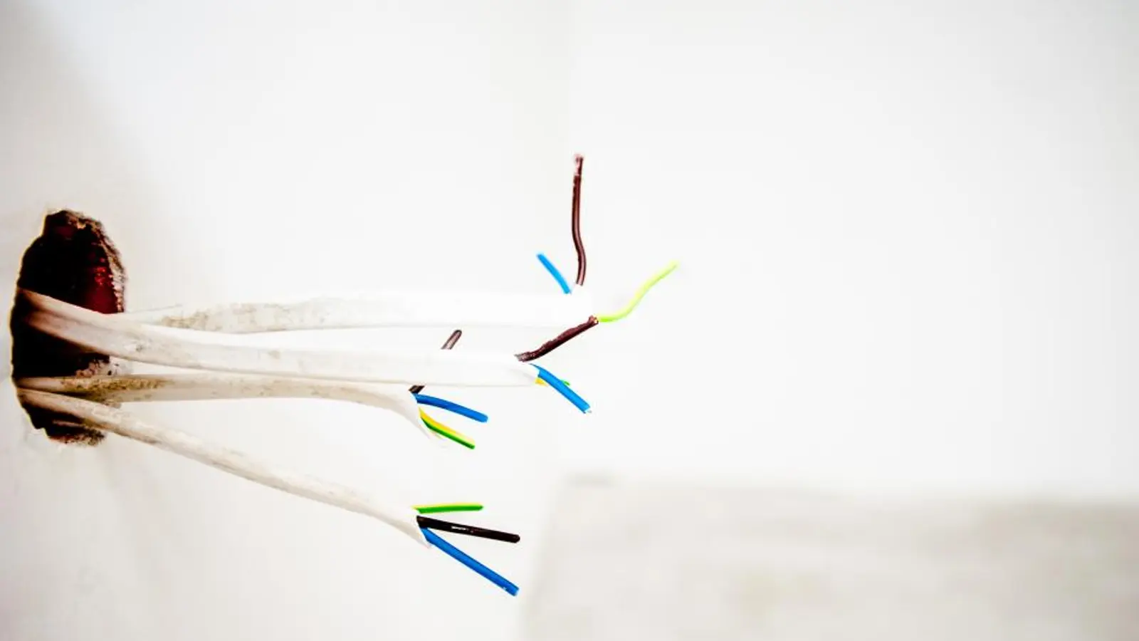 Loose wires coming out of a white wall