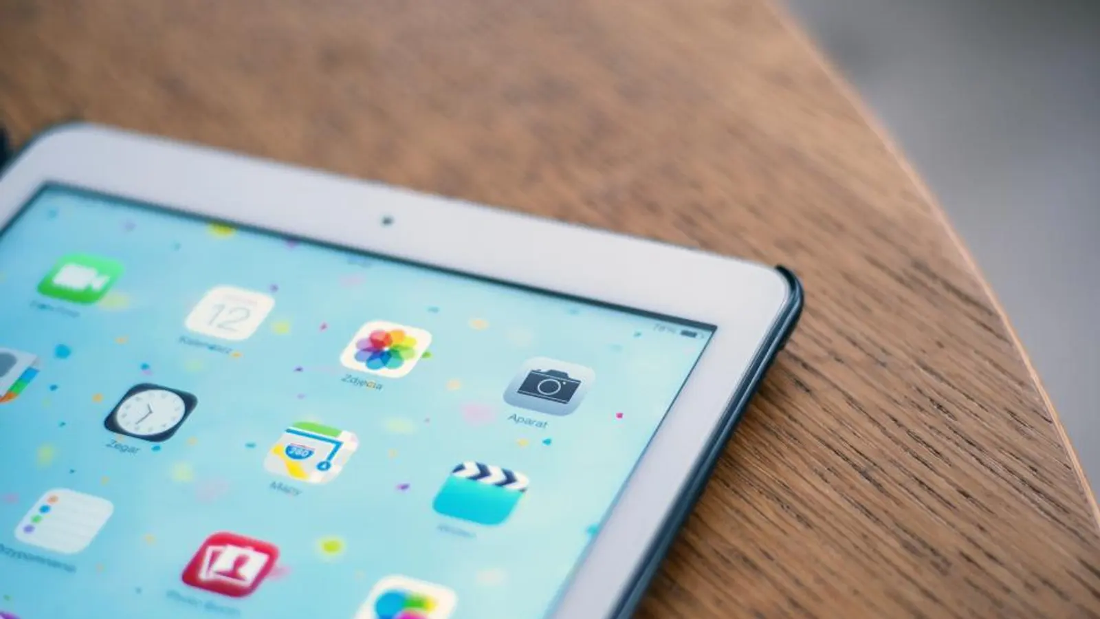 An iPad on a wooden table showing a screen of app icons