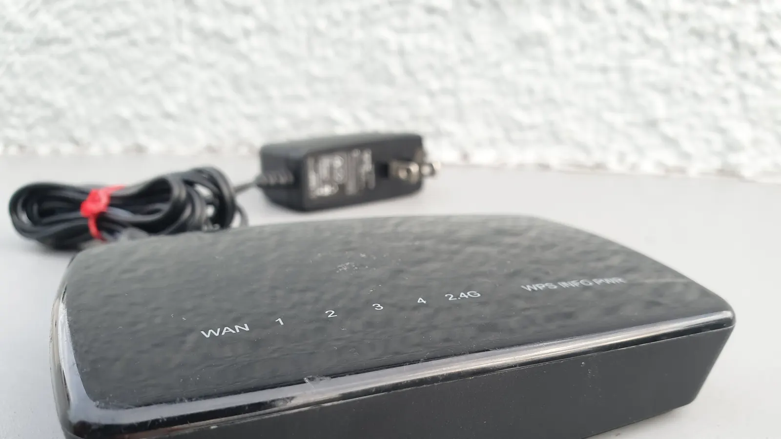 Home Wi-Fi router with its power cable on a white surface