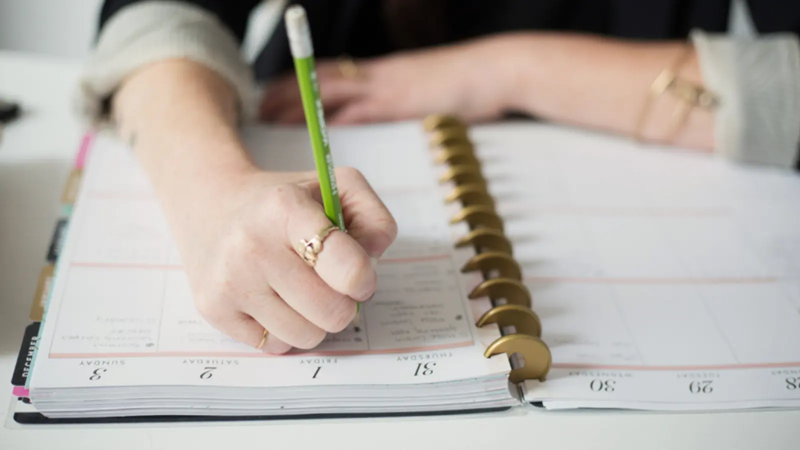 Hand schreibt mit Bleistift in einen Terminplaner