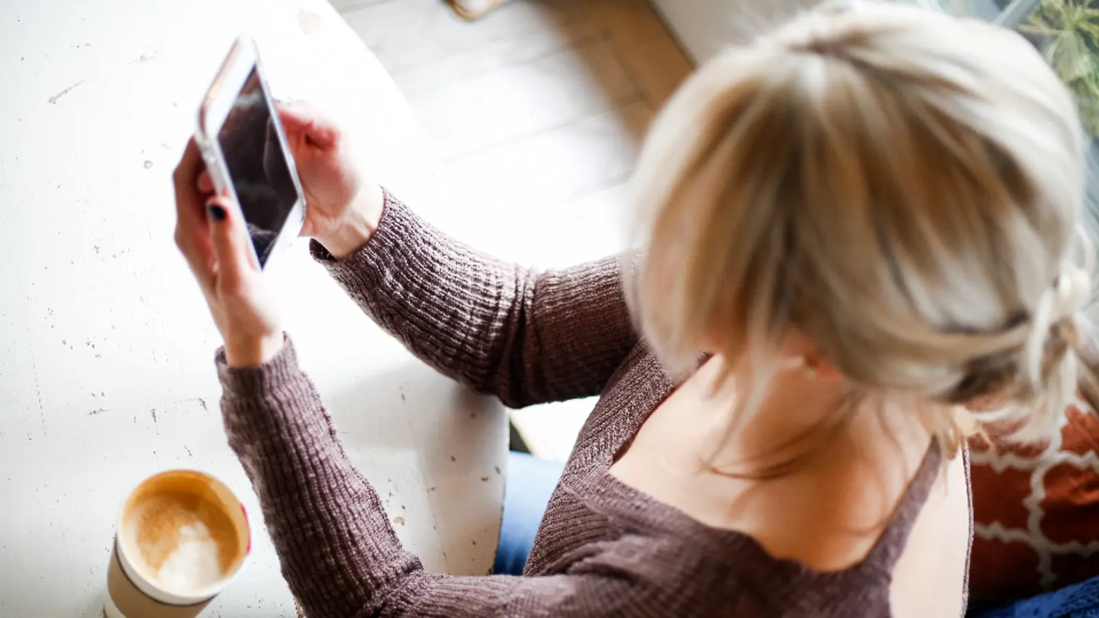 Frau schaut auf einem Sofa auf ein Tablet