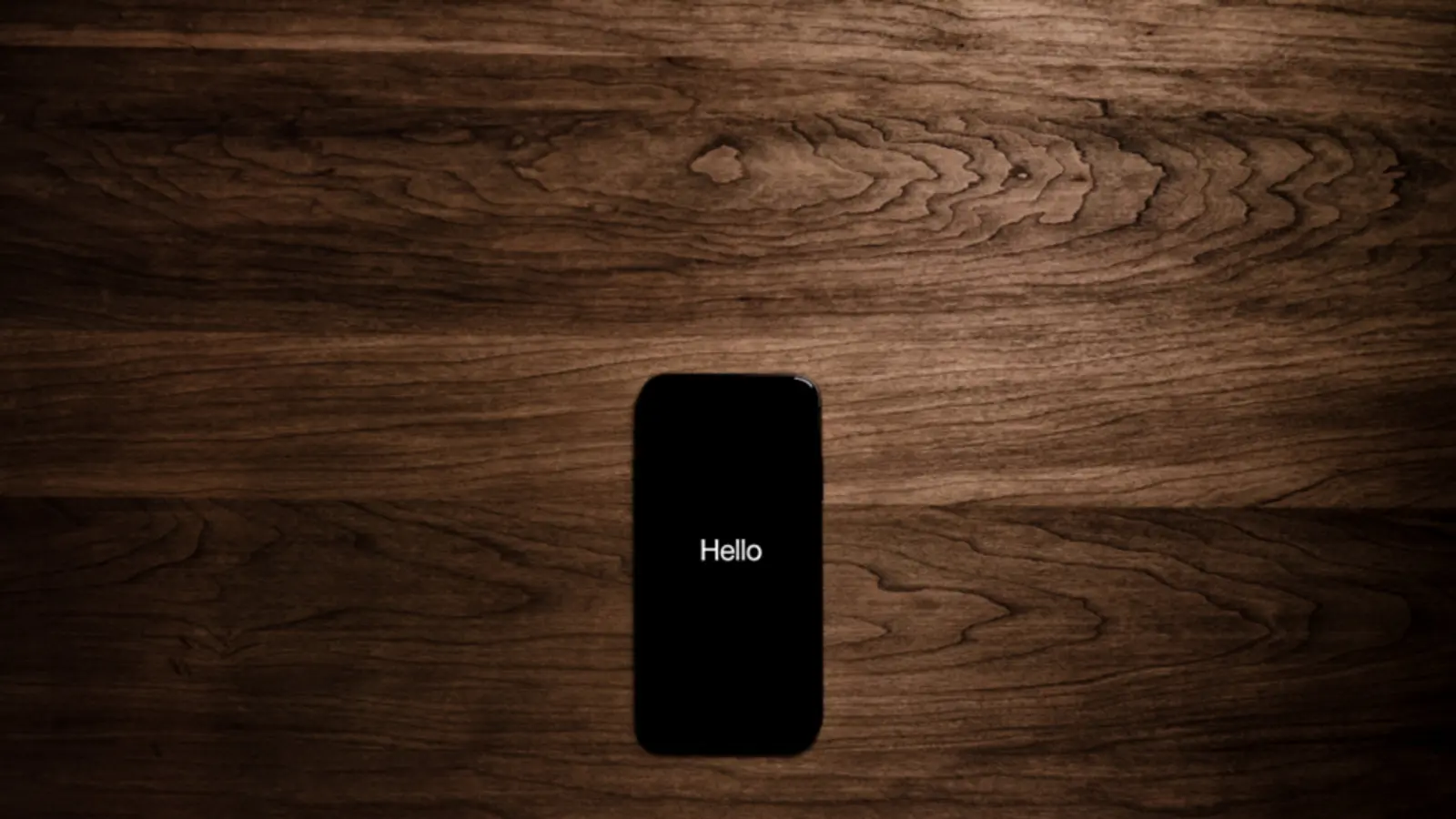 Smartphone mit dunklem Bildschirm auf einem Holztisch