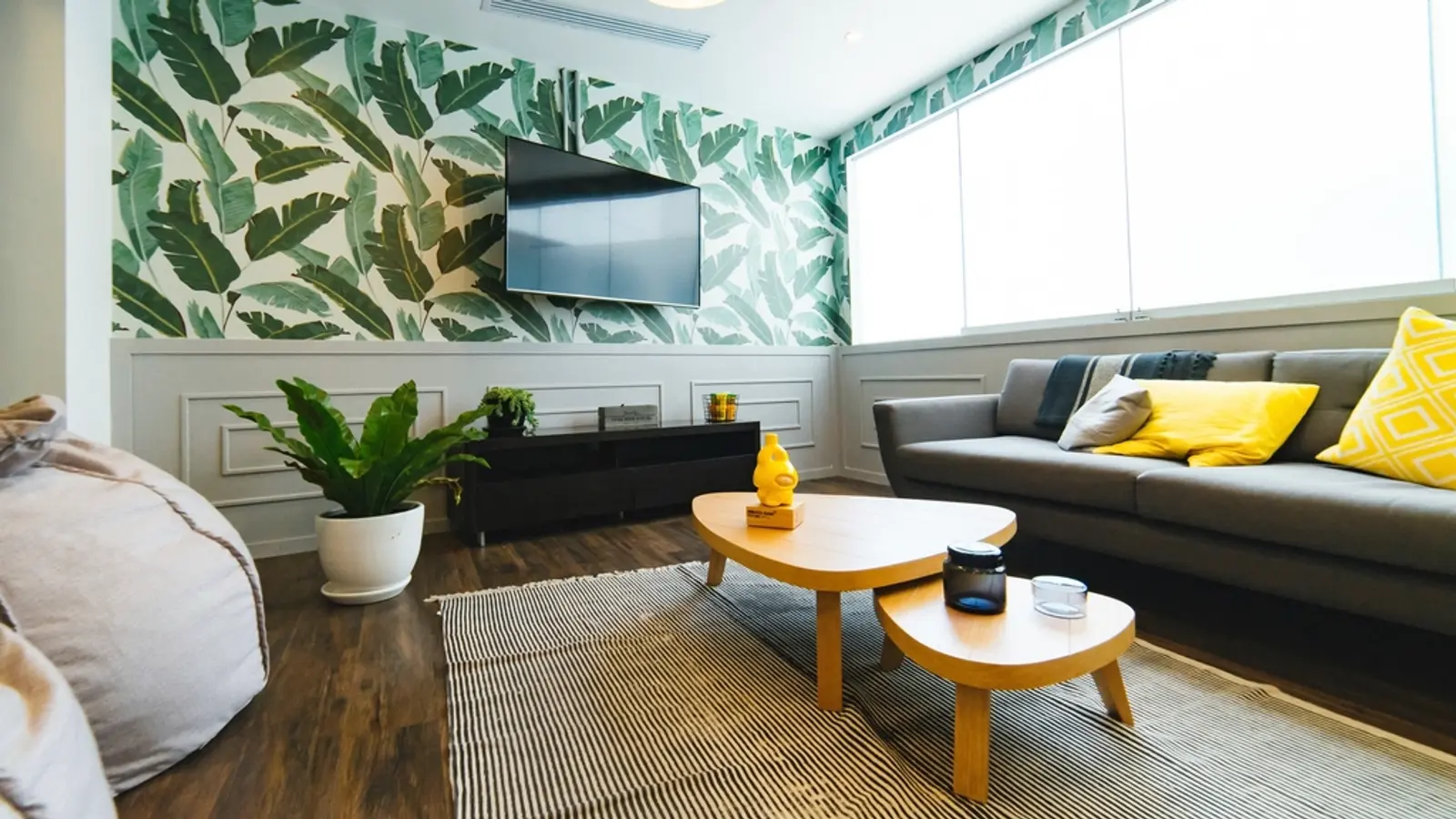 Wohnzimmer mit Fernseher an der Wand, Sofa und Pflanzen