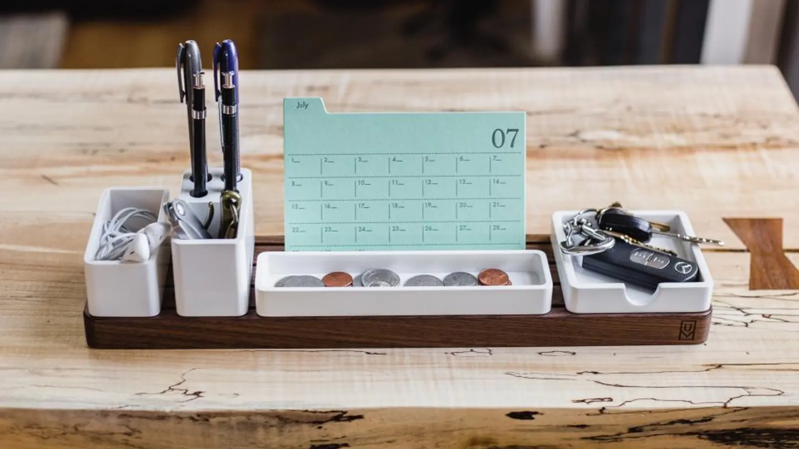 A desk organiser with a small calendar and pens