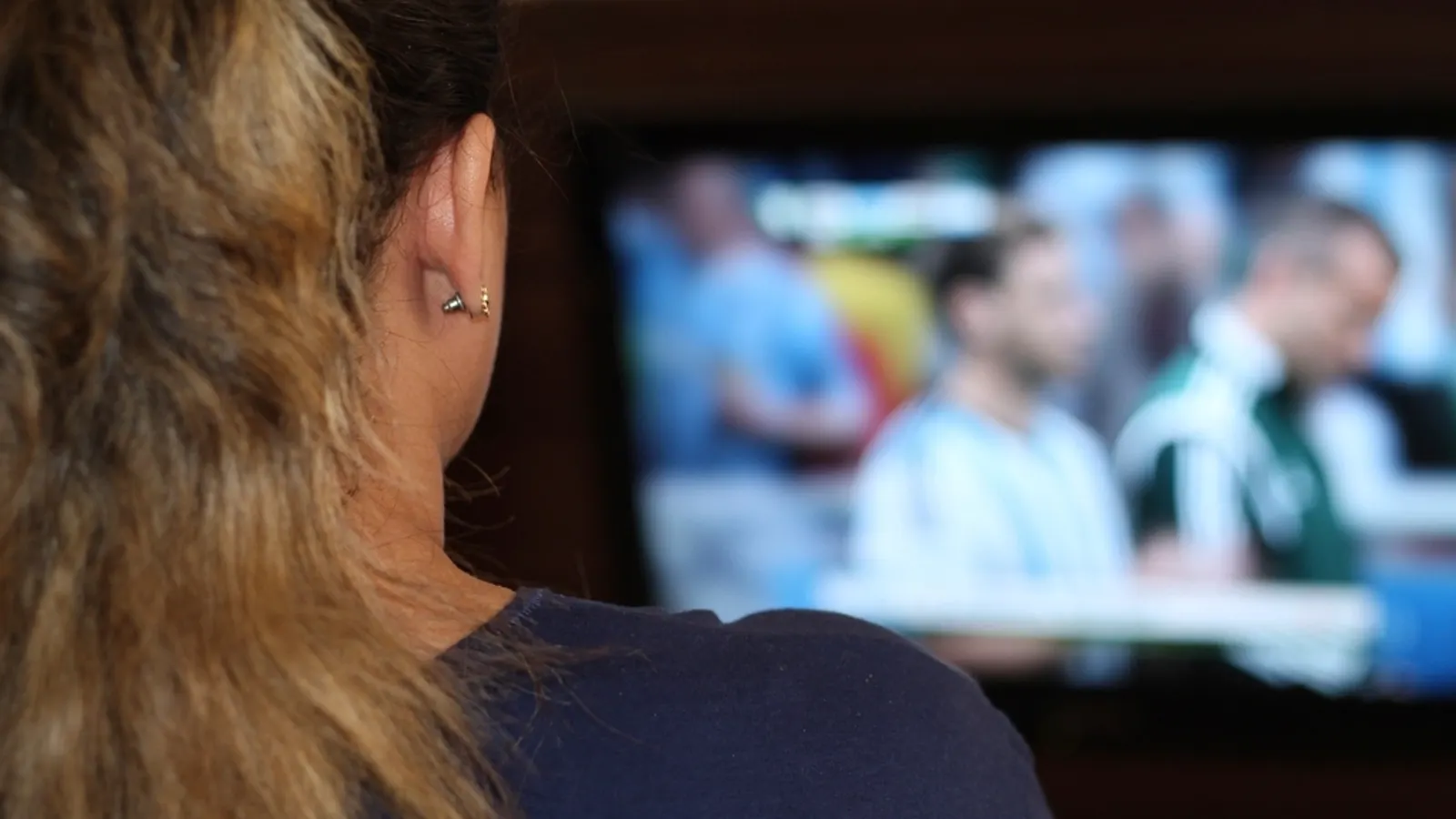Woman watching a football match on a large television