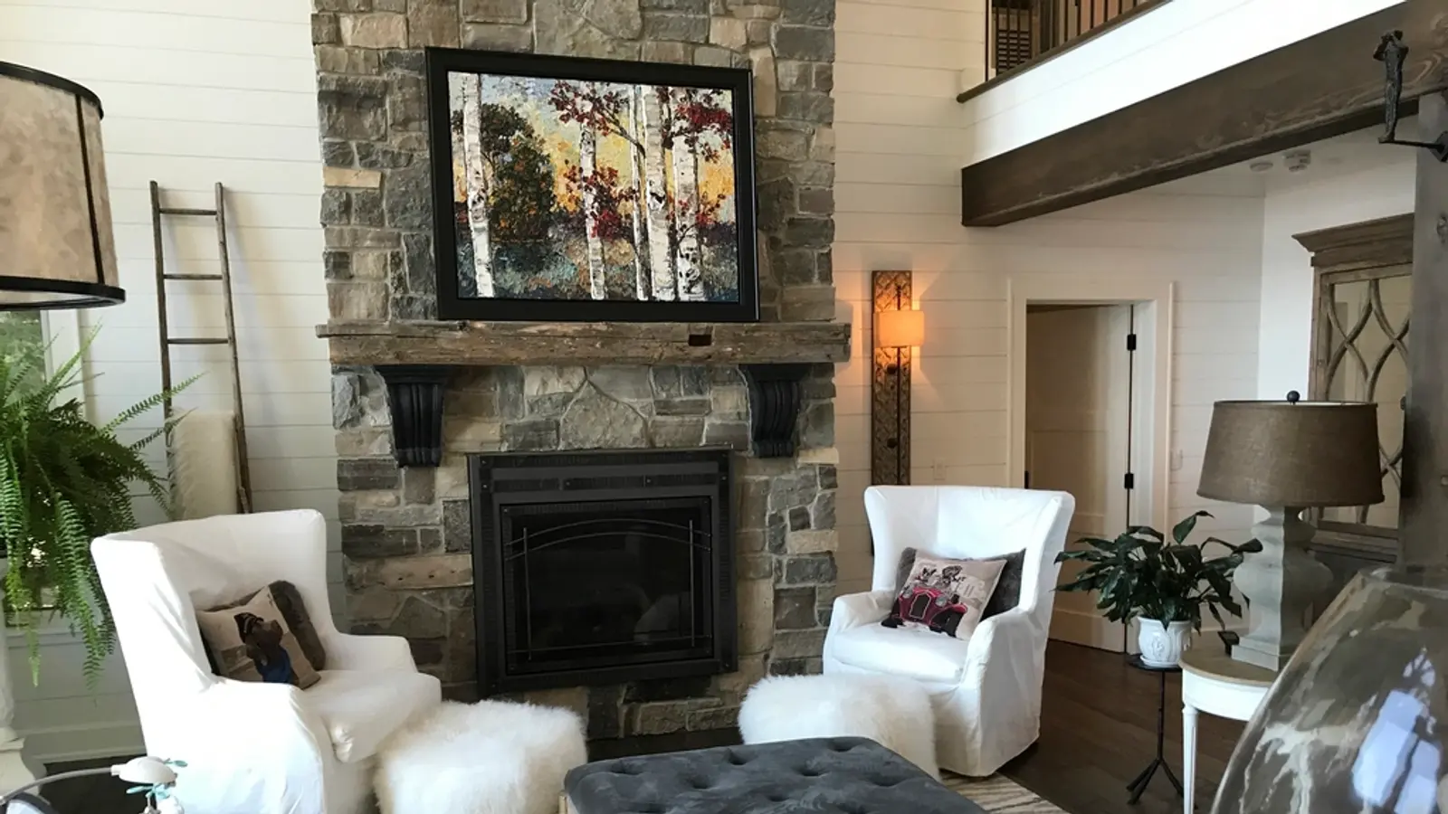 Salón acogedor con chimenea, sillones blancos y un mueble con tele