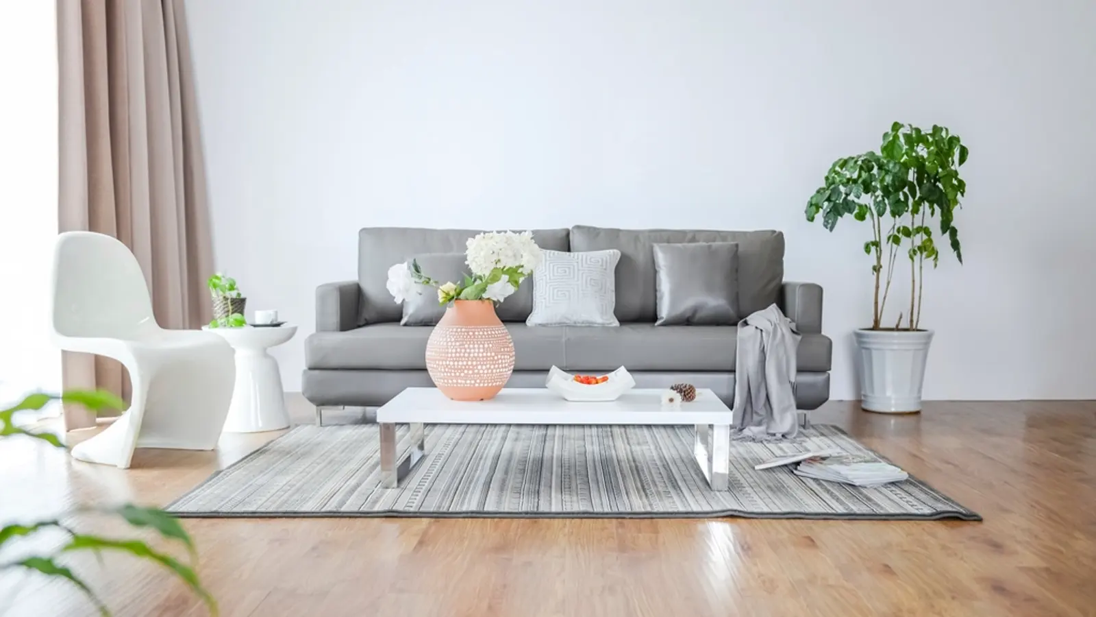 Salón luminoso con un sofá gris, mesa baja y plantas