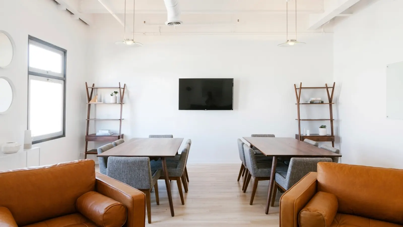 Sala amplia con un televisor en la pared y sillones de cuero