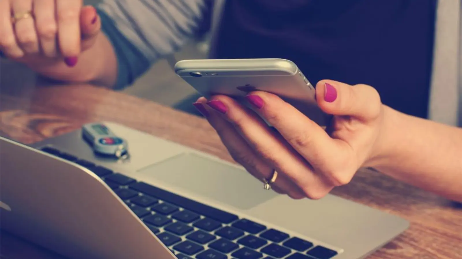 Main tenant un smartphone au-dessus du clavier d'un ordinateur portable