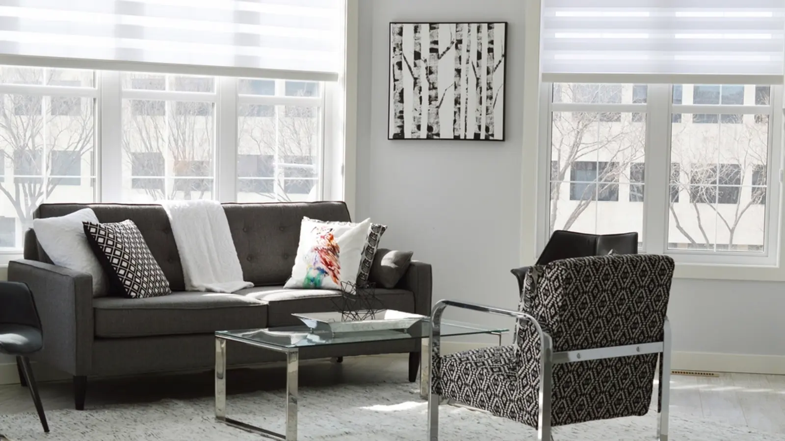 Salon minimaliste avec canapé gris et grandes fenêtres