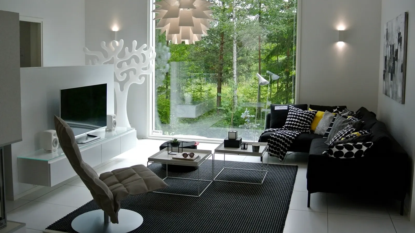 A modern living room with a TV and a big window onto trees