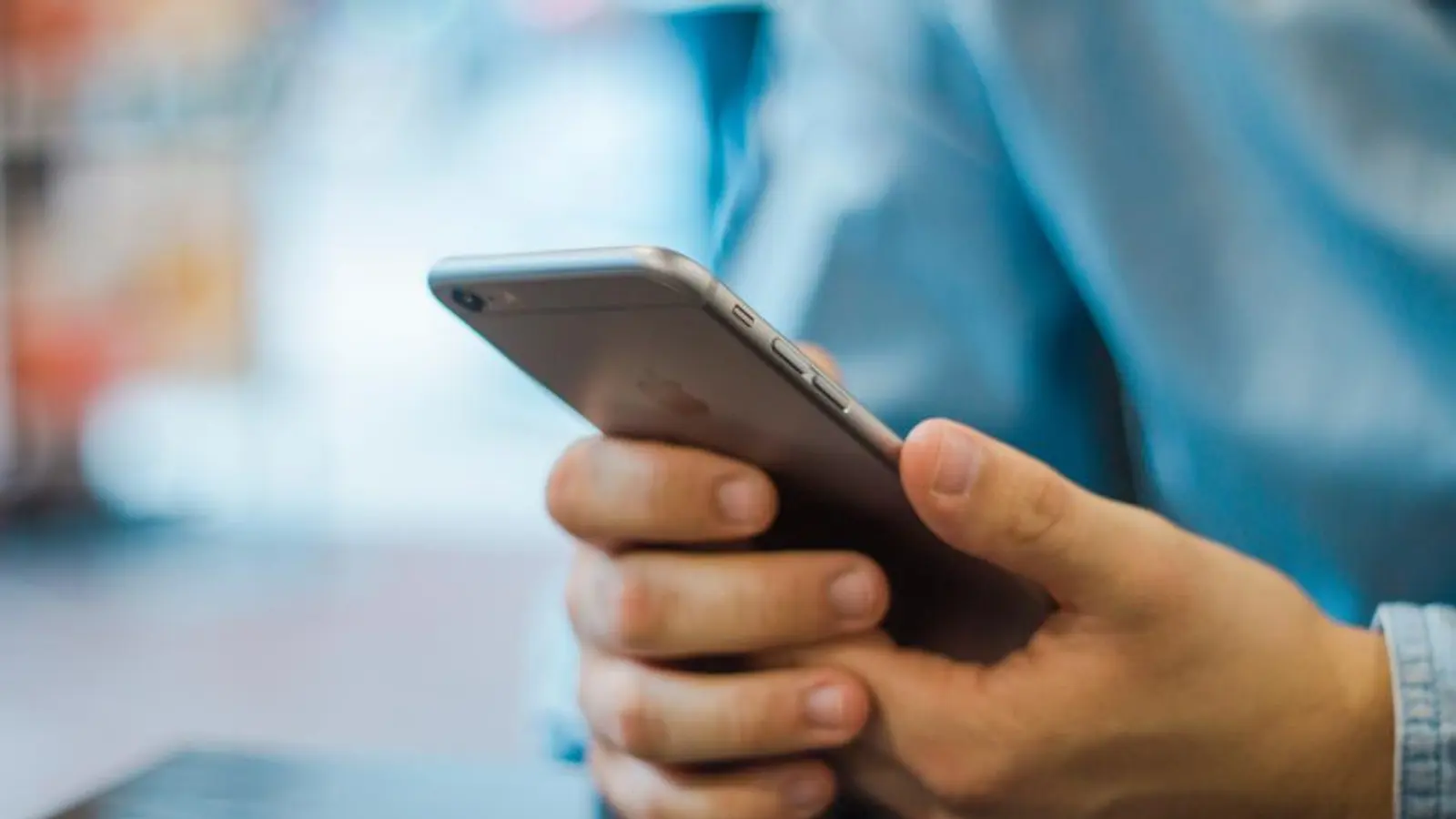 A hand holding an iPhone at a desk