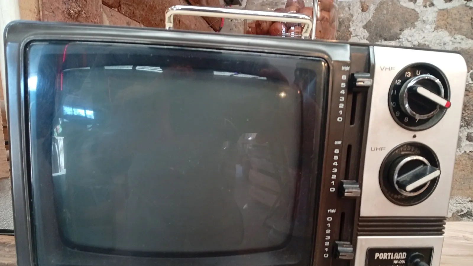 Vintage portable television with channel dials on a stone wall