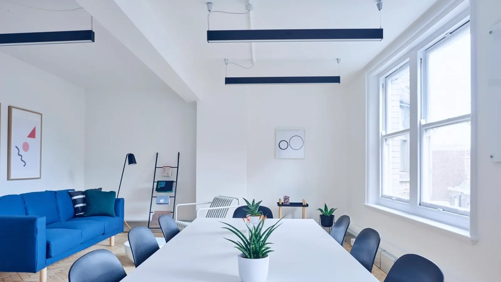 Ambiente luminoso con divano blu e un lungo tavolo bianco