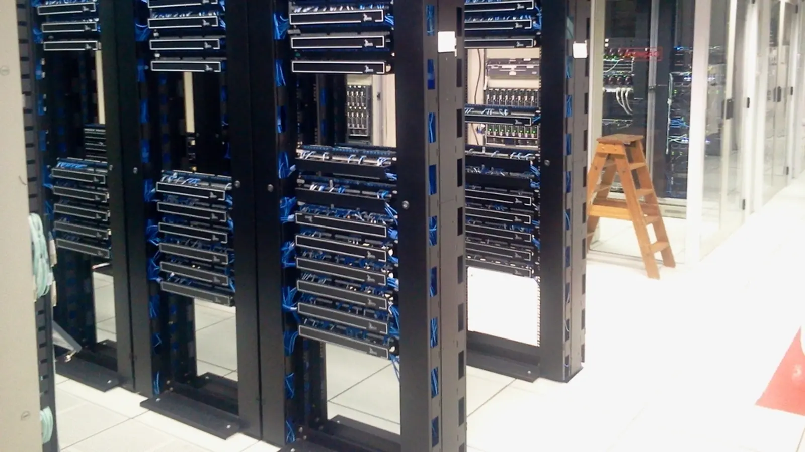 Rows of server racks with blue cabling in a data centre