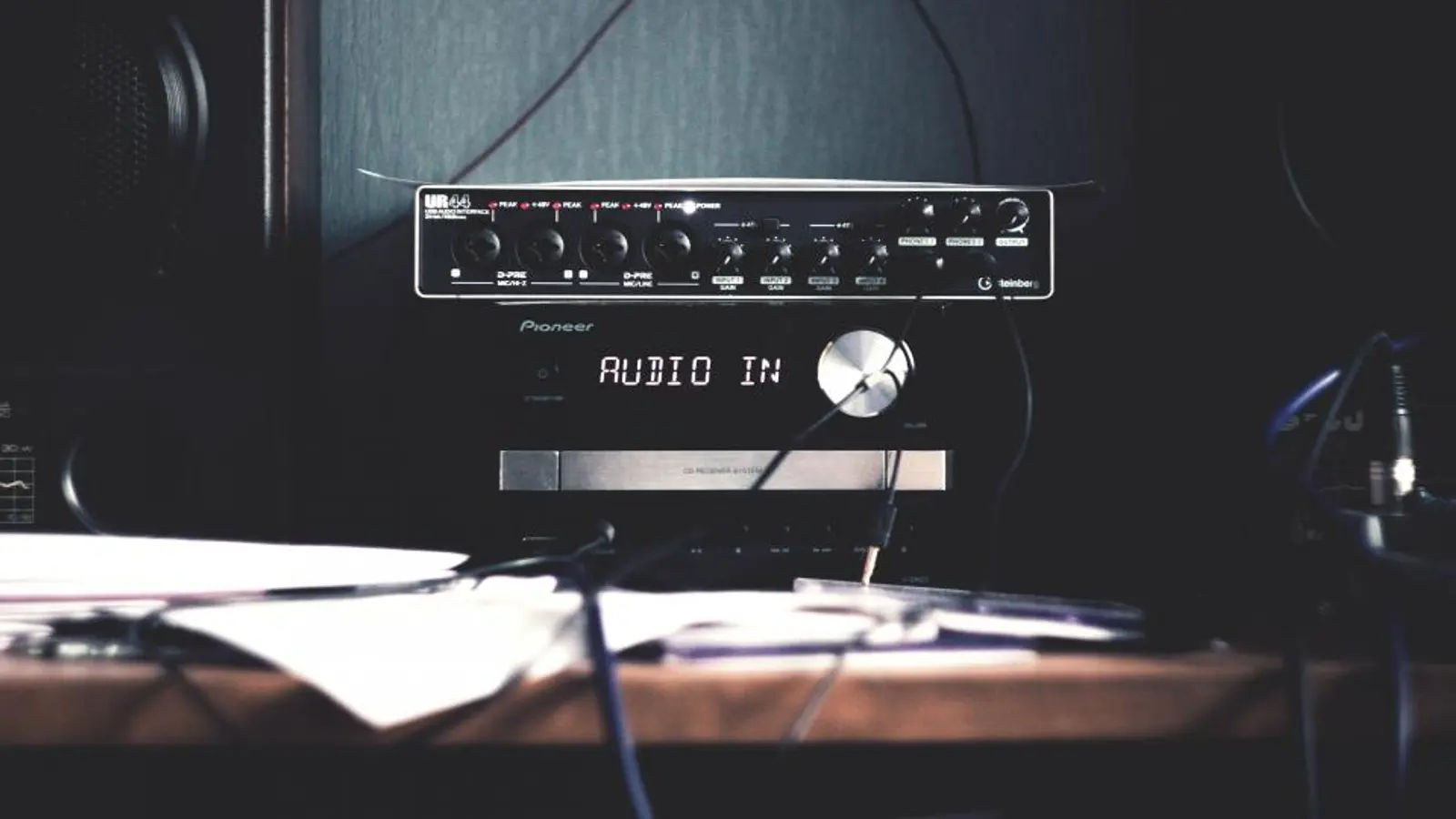 A hi-fi amplifier glowing under a screen in a dark room