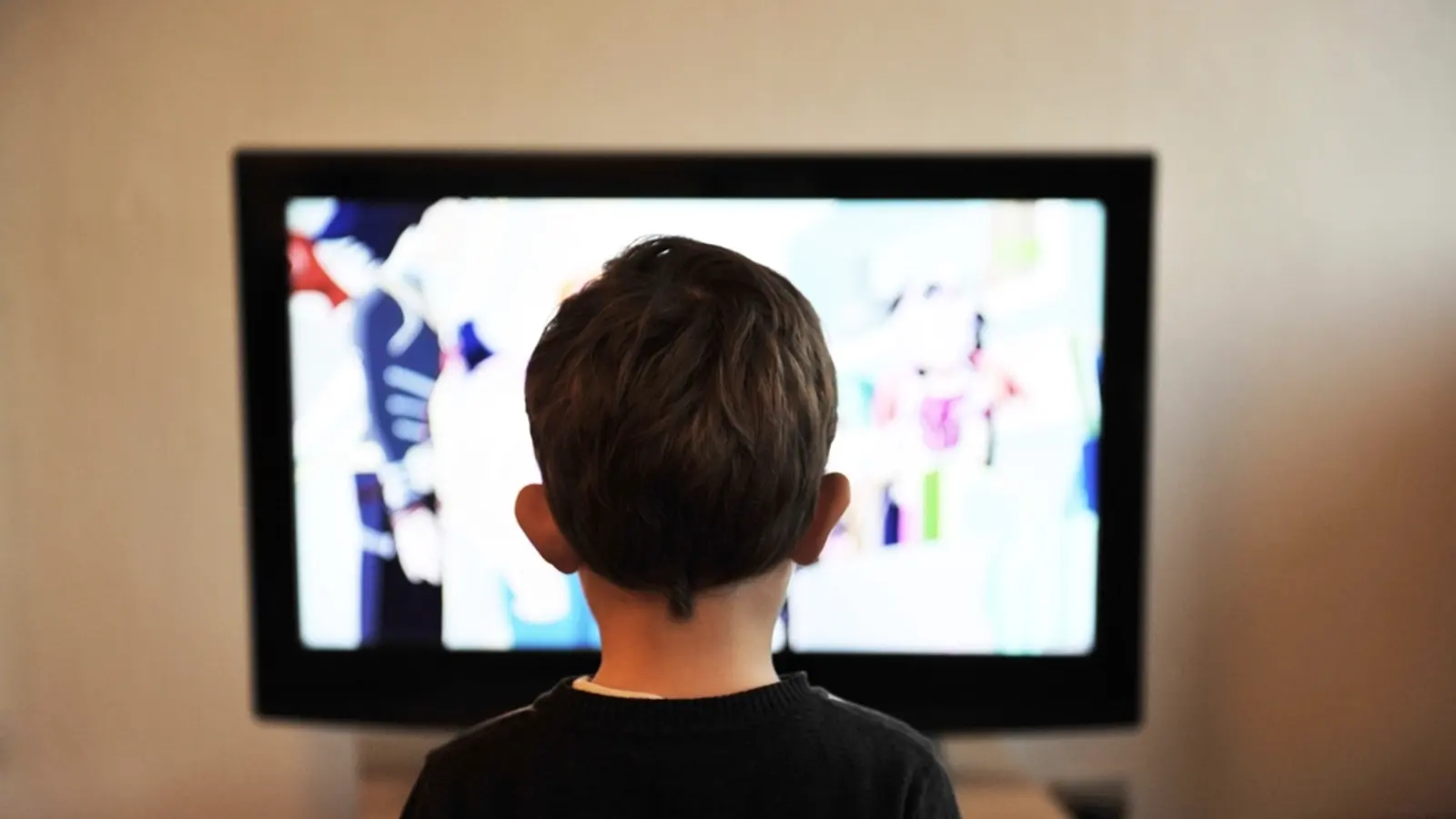 A child sitting in front of a television watching a cartoon