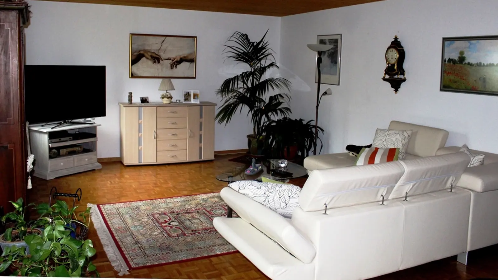 A bright living room with a TV and a white sofa
