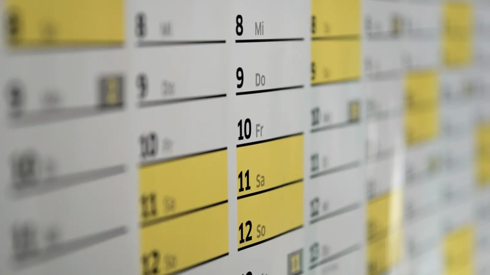 A blurred wall calendar with some dates highlighted in yellow