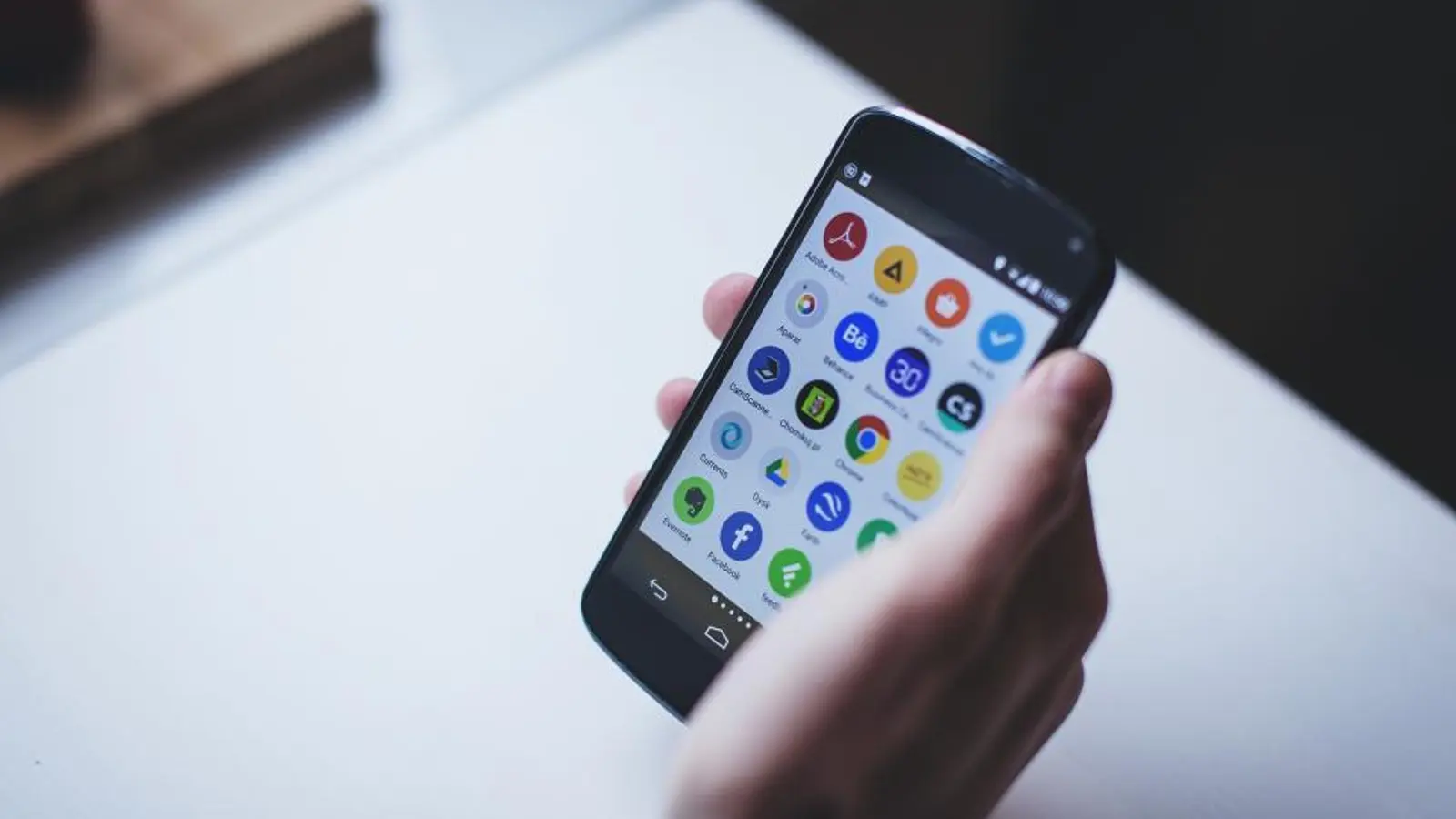 A hand holding a smartphone with a grid of app icons