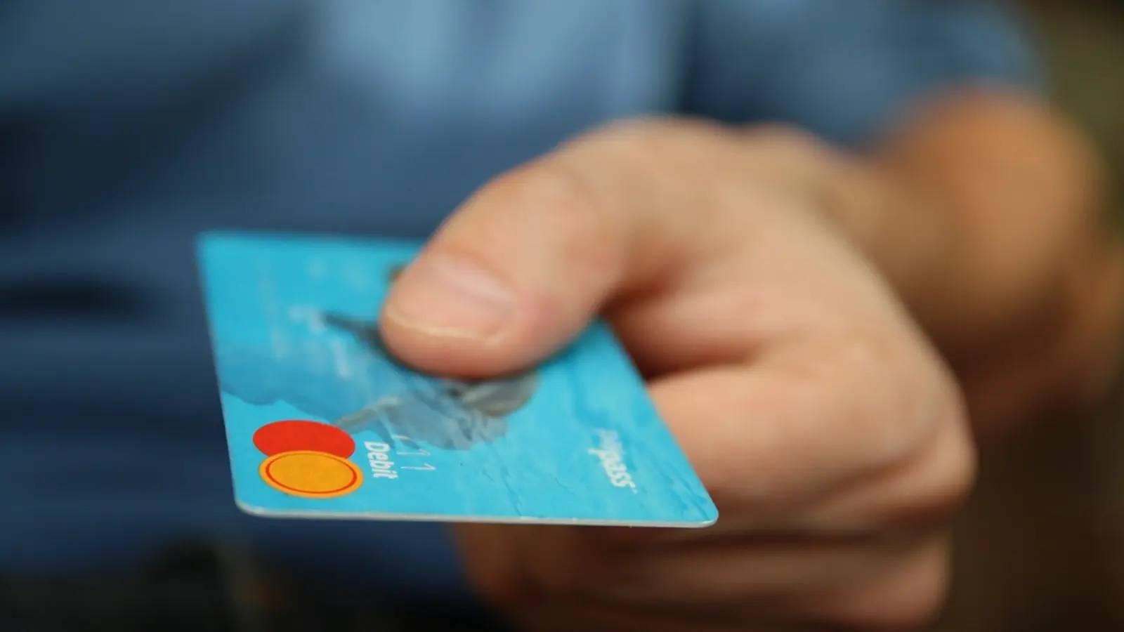 A hand holding out a blue credit card
