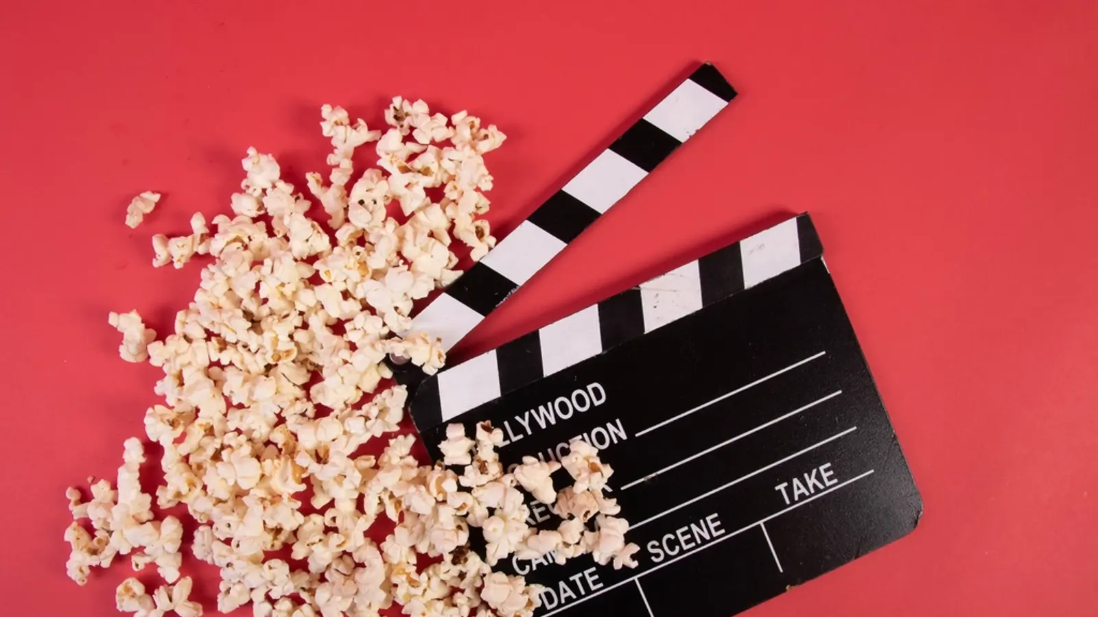 Popcorn spilling next to a film clapperboard on red
