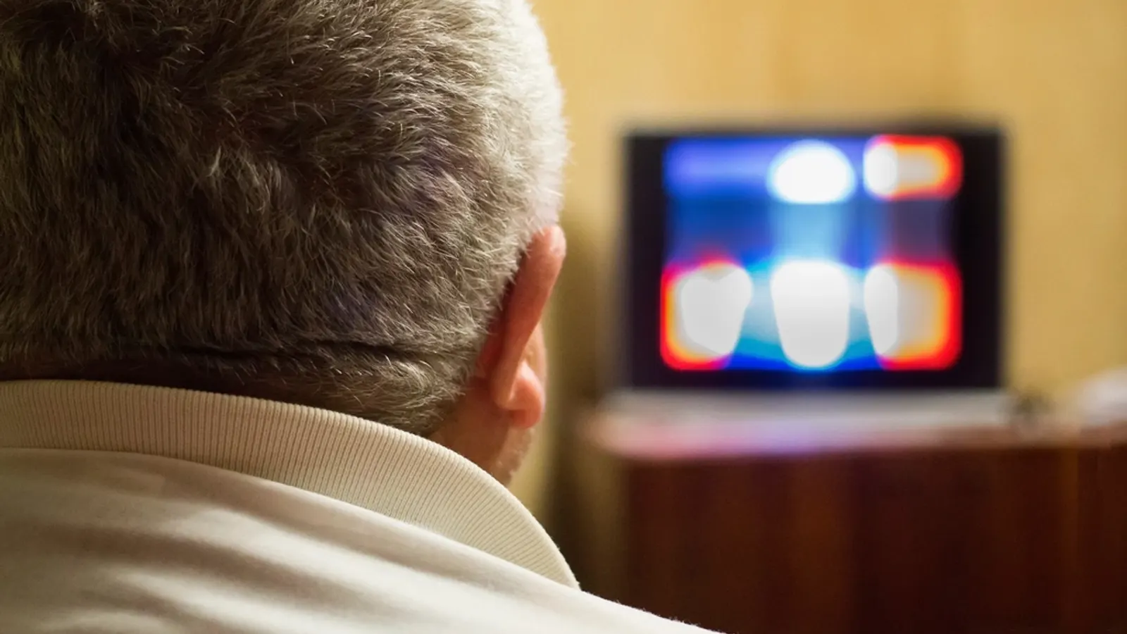 Man watching a television in a dim living room