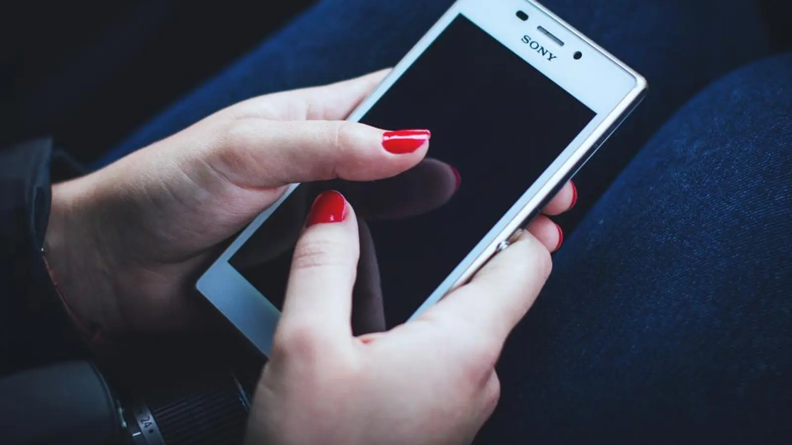 A woman holding a white smartphone in both hands
